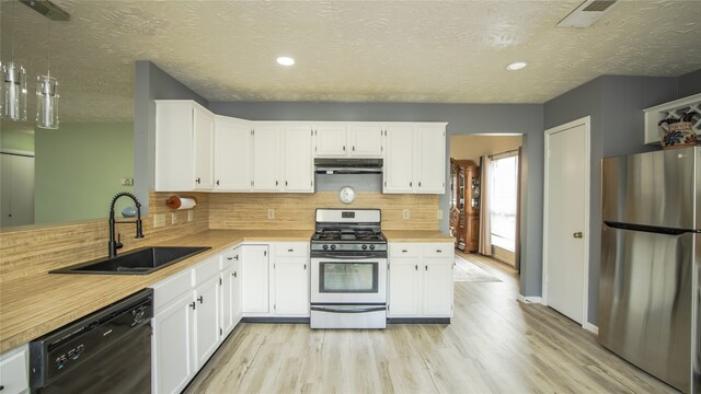 kitchen featuring appliances with stainless steel finishes, tasteful backsplash, white cabinetry, sink, and light hardwood / wood-style flooring