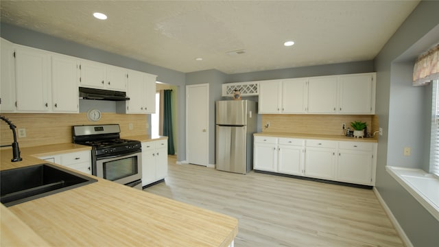 kitchen with white cabinetry, sink, light hardwood / wood-style flooring, and appliances with stainless steel finishes