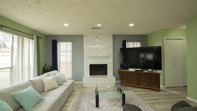 living room featuring a fireplace, light hardwood / wood-style floors, and a textured ceiling