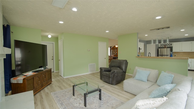 living room featuring a textured ceiling and light wood-type flooring