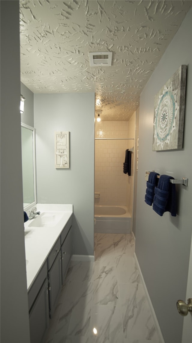 bathroom with tiled shower / bath, vanity, and a textured ceiling