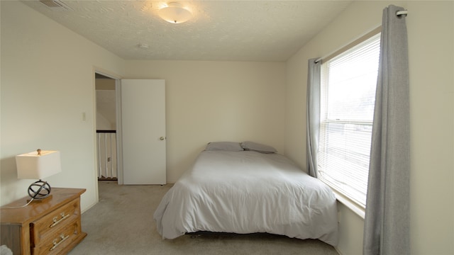 bedroom with light colored carpet and a textured ceiling