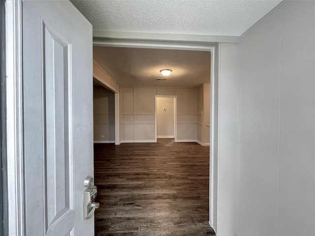 hallway featuring dark wood-type flooring and a textured ceiling