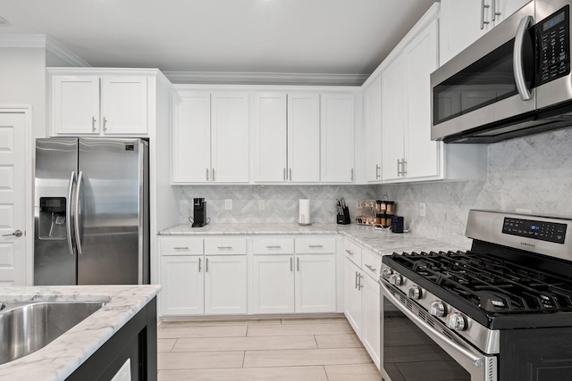 kitchen featuring white cabinetry, decorative backsplash, light stone countertops, and appliances with stainless steel finishes