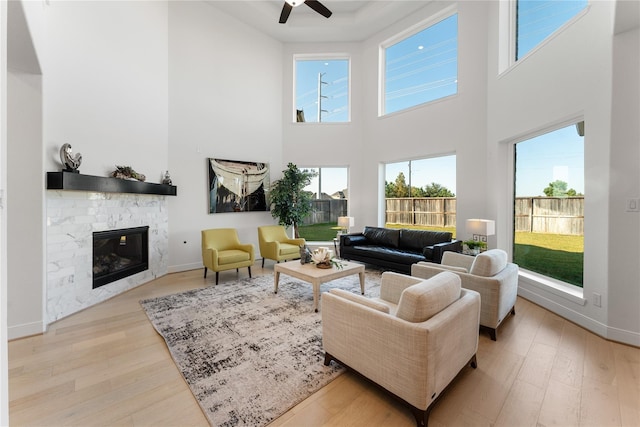 living room featuring ceiling fan, a fireplace, and light hardwood / wood-style flooring