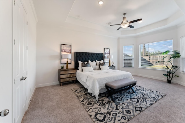 carpeted bedroom featuring a tray ceiling and ceiling fan