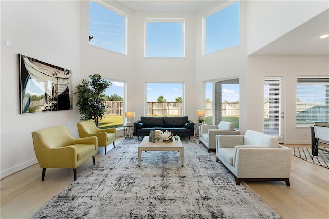 living room with plenty of natural light, light hardwood / wood-style flooring, and a high ceiling