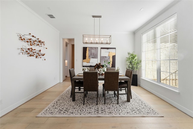 dining space with an inviting chandelier, light hardwood / wood-style flooring, and ornamental molding