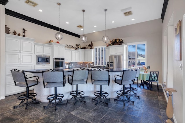 kitchen with a spacious island, a kitchen bar, appliances with stainless steel finishes, pendant lighting, and white cabinets