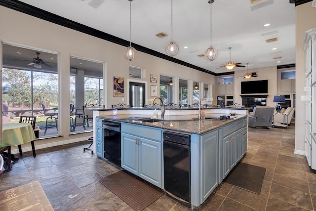 kitchen with sink, crown molding, hanging light fixtures, an island with sink, and dark stone counters