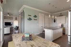 kitchen featuring white cabinetry, a center island, ornamental molding, ceiling fan, and a barn door