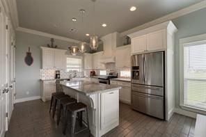 kitchen with ornamental molding, appliances with stainless steel finishes, a center island, and white cabinets