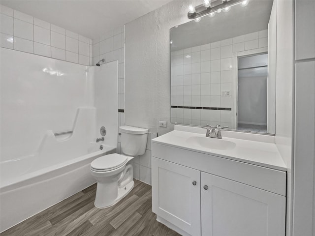 full bathroom featuring toilet, bathing tub / shower combination, wood-type flooring, tile walls, and vanity