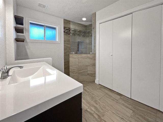 bathroom featuring vanity and tiled shower