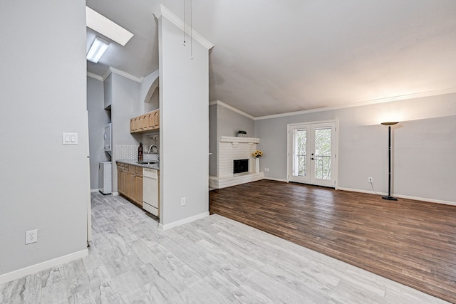 unfurnished living room featuring lofted ceiling, sink, ornamental molding, and a brick fireplace