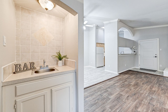 bathroom featuring sink, backsplash, wood-type flooring, and ornamental molding