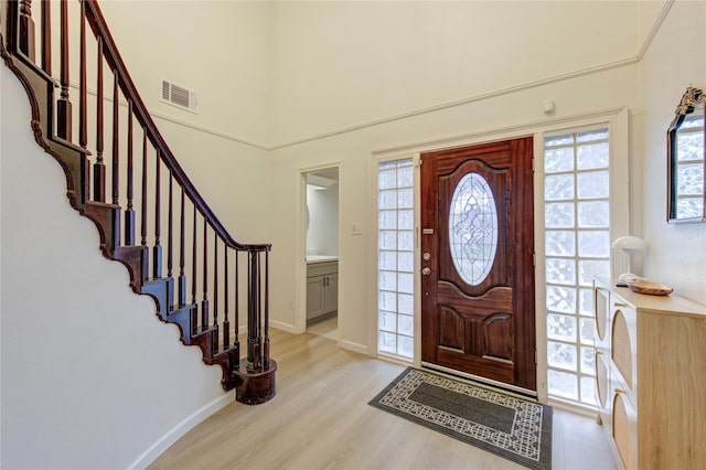 entrance foyer featuring a towering ceiling and light wood-type flooring