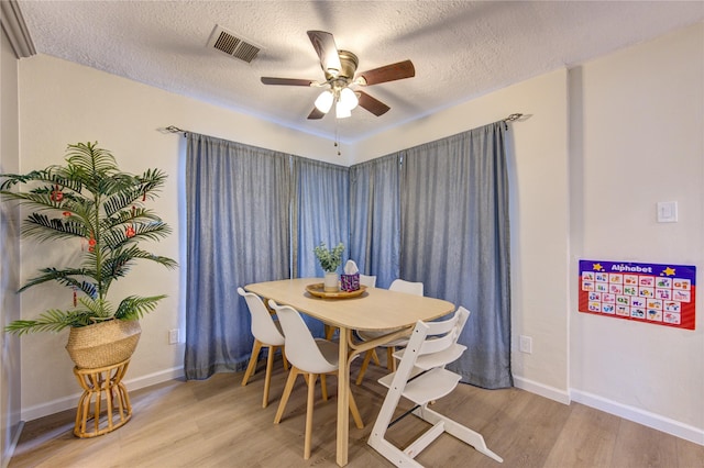 dining area with ceiling fan, a textured ceiling, and light wood-type flooring