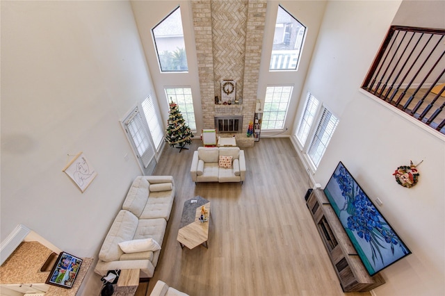 living room with a healthy amount of sunlight, a fireplace, light hardwood / wood-style floors, and a high ceiling