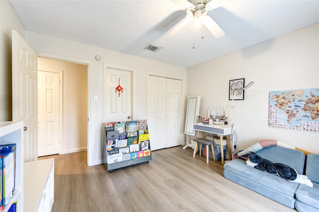 recreation room featuring ceiling fan, a textured ceiling, and light wood-type flooring