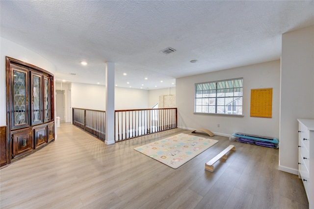 workout room featuring a textured ceiling and light hardwood / wood-style flooring