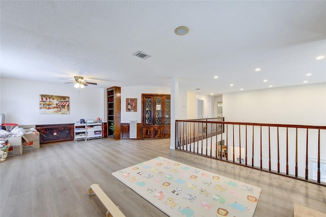 interior space with ceiling fan, a textured ceiling, and light wood-type flooring