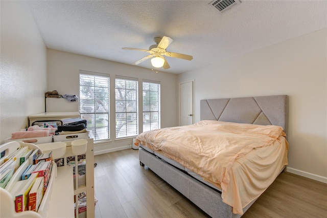 bedroom featuring hardwood / wood-style flooring, ceiling fan, and a textured ceiling