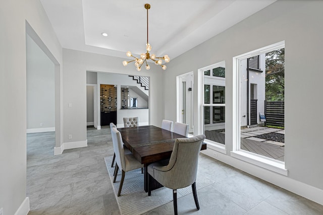 dining space featuring an inviting chandelier and a raised ceiling