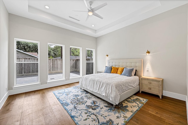 bedroom featuring a raised ceiling, ceiling fan, and dark hardwood / wood-style flooring