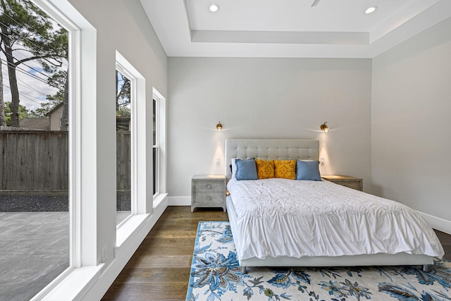 bedroom with a tray ceiling and dark hardwood / wood-style floors