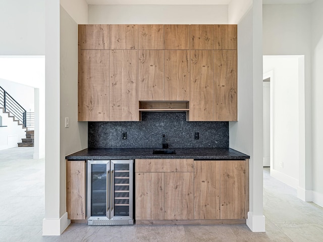 kitchen with tasteful backsplash, beverage cooler, sink, and dark stone countertops