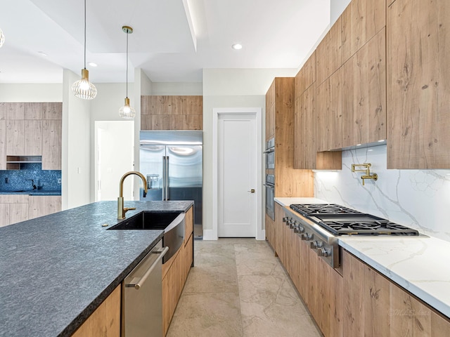 kitchen featuring sink, backsplash, dark stone counters, hanging light fixtures, and stainless steel appliances