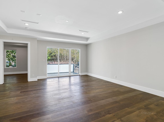 empty room with a raised ceiling and dark wood-type flooring