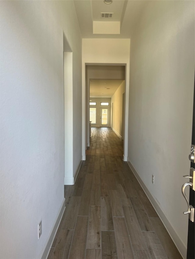 corridor featuring a raised ceiling and dark hardwood / wood-style flooring