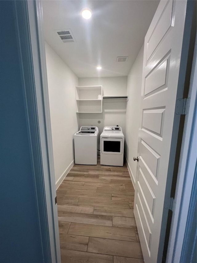 laundry area with independent washer and dryer and light hardwood / wood-style flooring