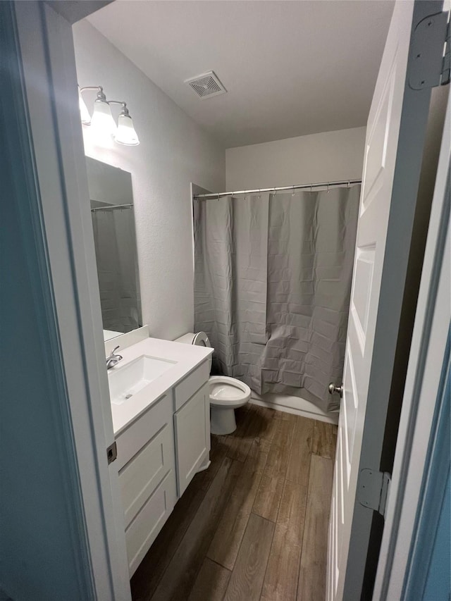 full bathroom with wood-type flooring, toilet, vanity, and shower / bath combo