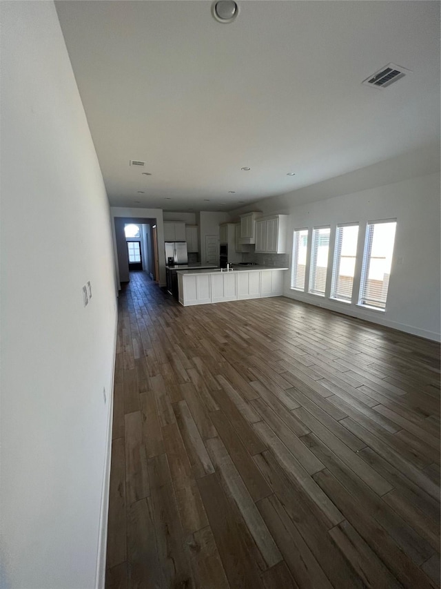 unfurnished living room featuring plenty of natural light and dark hardwood / wood-style floors