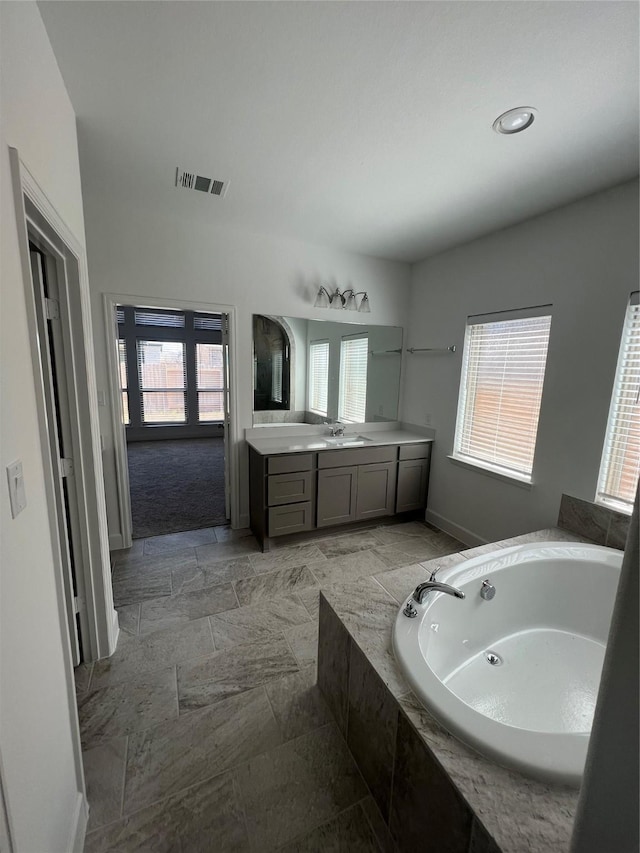 bathroom featuring vanity and a relaxing tiled tub