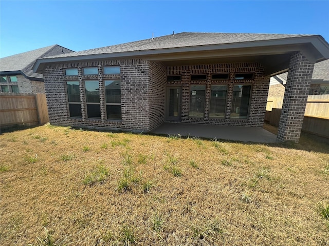 back of property with a yard and a patio