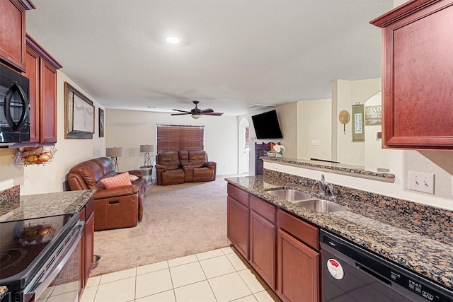 kitchen with sink, ceiling fan, black appliances, light colored carpet, and dark stone counters