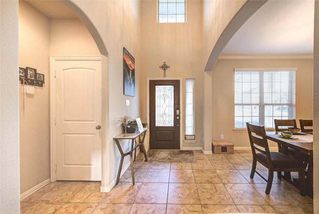 tiled foyer featuring crown molding and a high ceiling