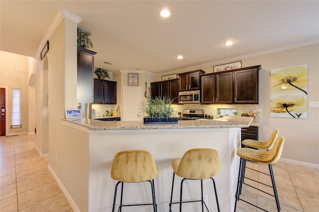 kitchen featuring appliances with stainless steel finishes, ornamental molding, light stone countertops, light tile patterned flooring, and kitchen peninsula