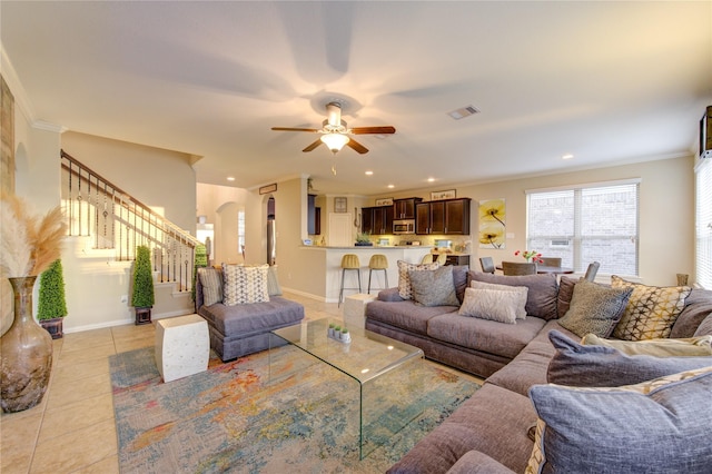 living room with light tile patterned flooring, ornamental molding, and ceiling fan