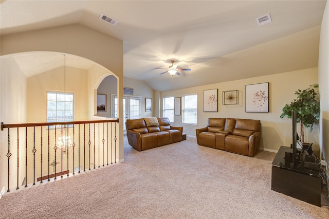 carpeted living room with lofted ceiling and ceiling fan with notable chandelier