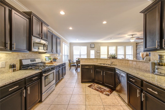 kitchen with sink, light tile patterned floors, light stone countertops, and appliances with stainless steel finishes