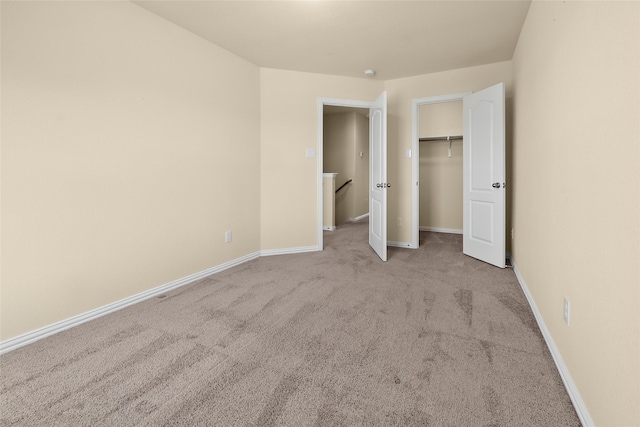 unfurnished bedroom featuring a walk in closet, light colored carpet, and a closet