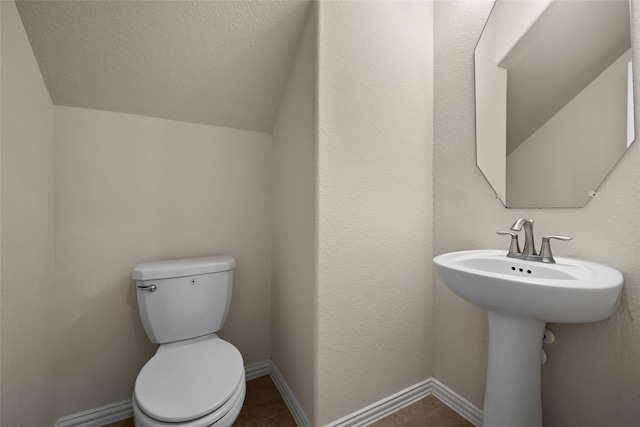 bathroom featuring a textured ceiling, vaulted ceiling, and toilet