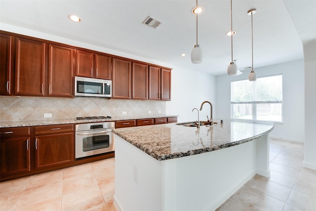 kitchen featuring sink, light stone counters, hanging light fixtures, appliances with stainless steel finishes, and backsplash