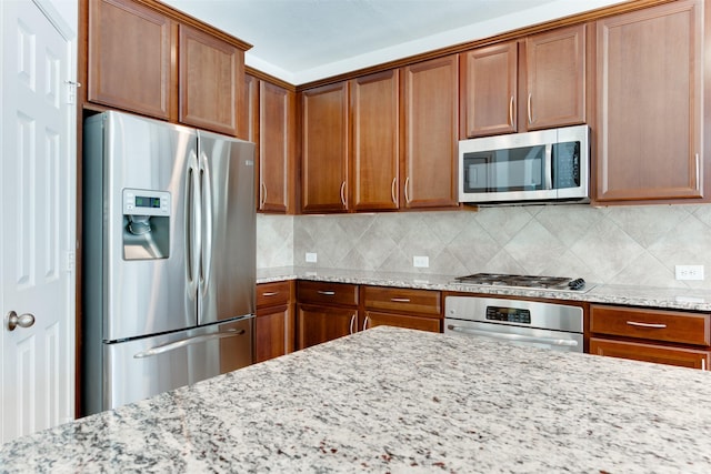 kitchen featuring tasteful backsplash, stainless steel appliances, and light stone countertops