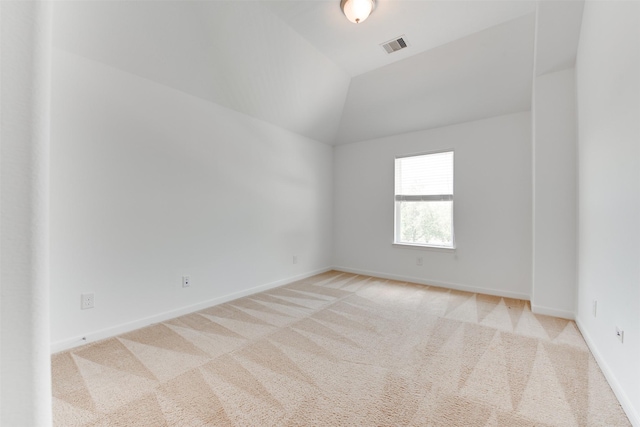 unfurnished room featuring vaulted ceiling and light carpet